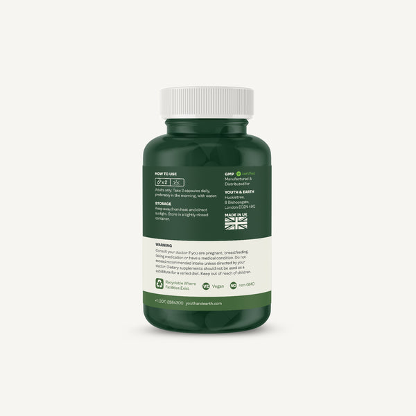 A dark green supplement bottle with a white cap, showing the back label with usage, storage, and warnings, on a light off-white background.