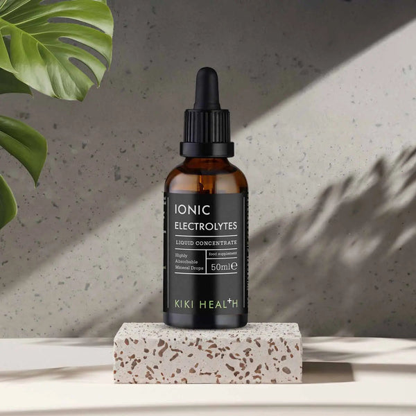 Kiki Health Ionic Electrolytes bottle on a stone block with a plant in the corner