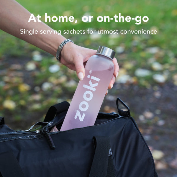 Person holding a pink water bottle labeled 'zooki' with text about single serving sachets for convenience.