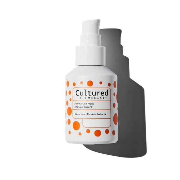 A white bottle with orange dots labeled 'Cultured' with a spray pump, containing a skin care product.