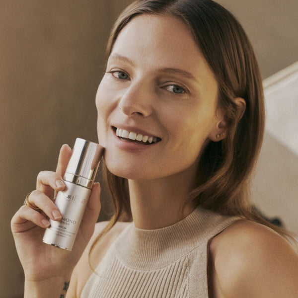 a model holding a bottle of Natura Bisse Diamond Extreme Serum close to her face