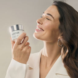 a model holding a jar of Natura Bisse Diamond Luminous Perfecting Cream close to her face