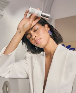 a model holding a bottle of Natura Bisse Diamond White Serum close to her face