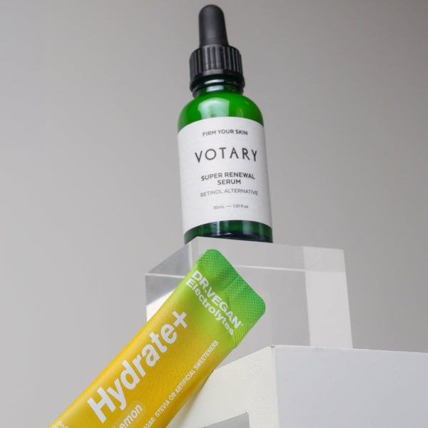 Votary serum bottle and Hydrate+ lemon drink package on a gray background