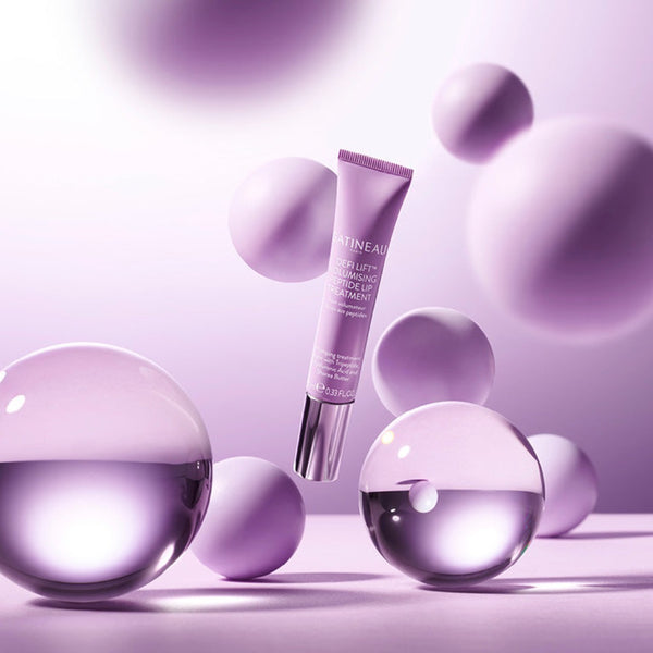 Gatineau Defi Lift Volumising Peptide Lip Treatment tube floating with purple balls around it