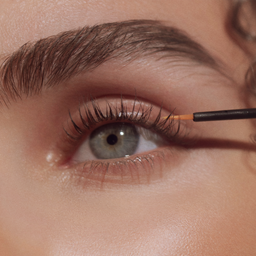 a close up of a women applying the eyelash conditioner 