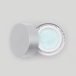 Cosmetic jar with light blue cream inside on a white background