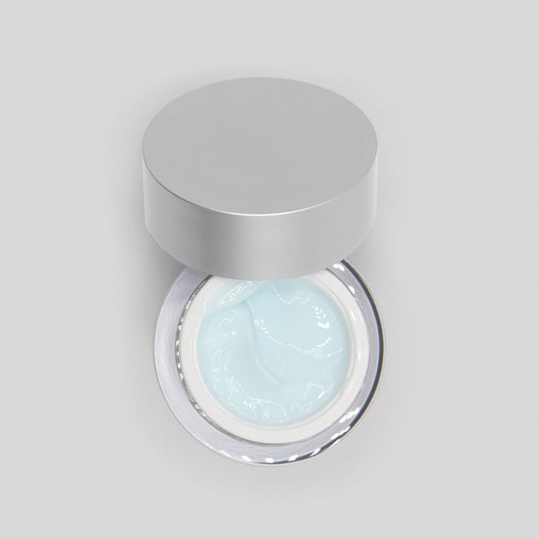 Jar of light blue cream with a silver lid on a gray background