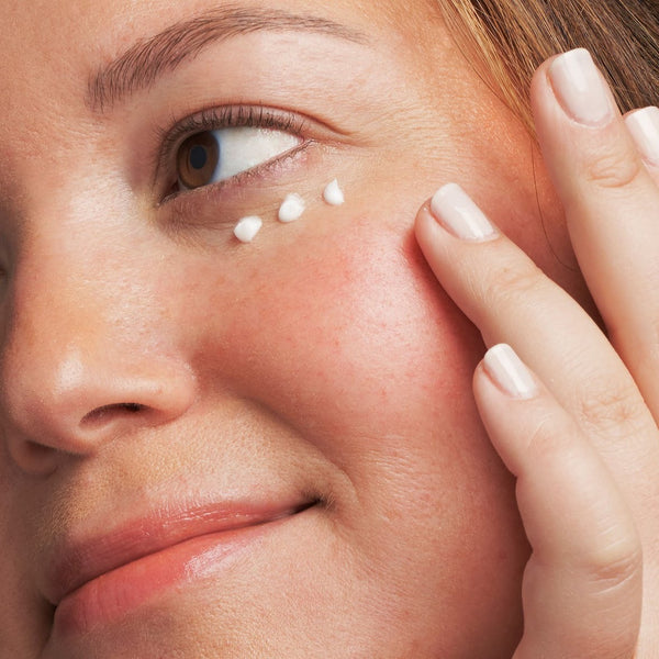 model applying eye cream to her face