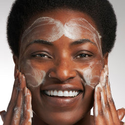 model applying cleanser to her face