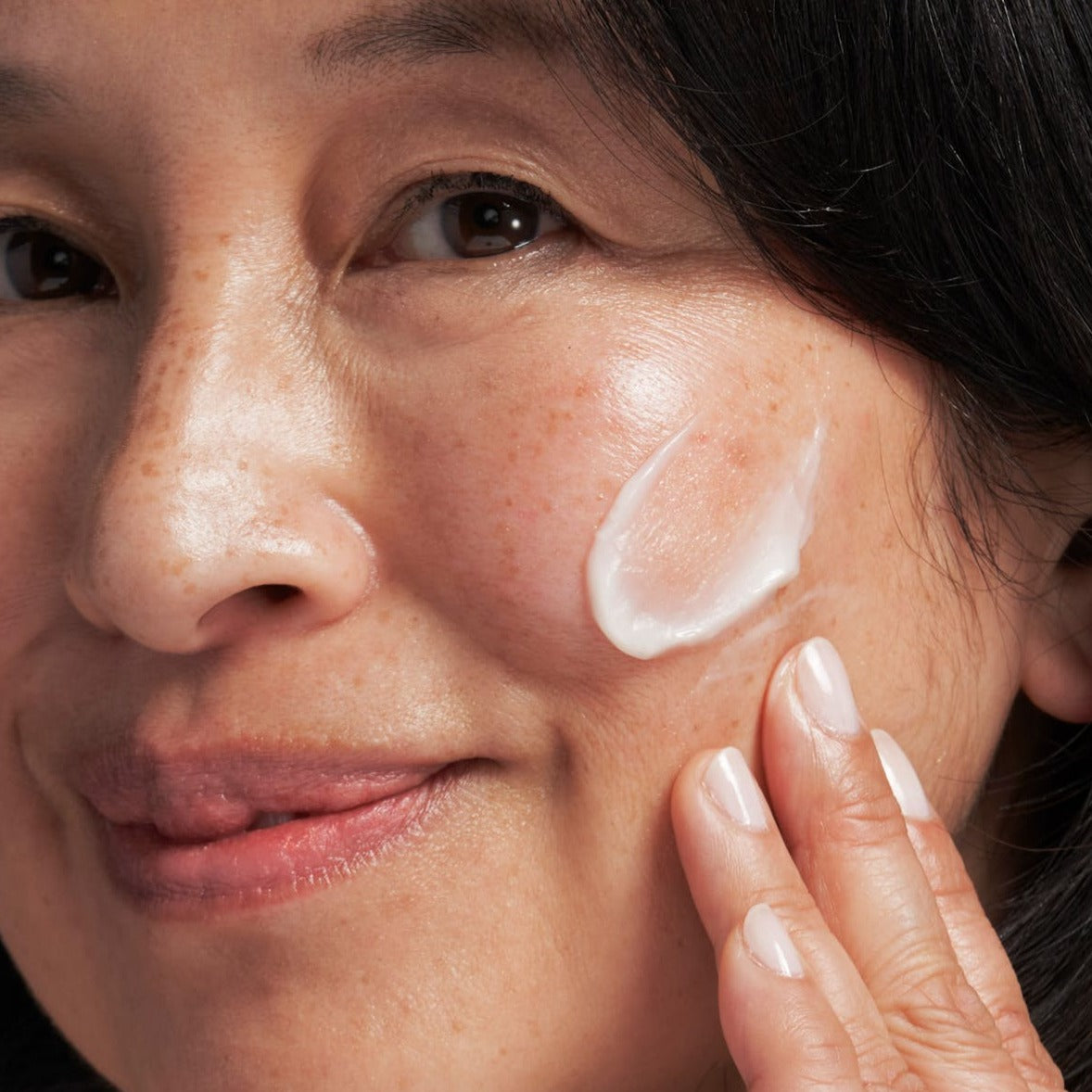 model applying skin brightener to her skin