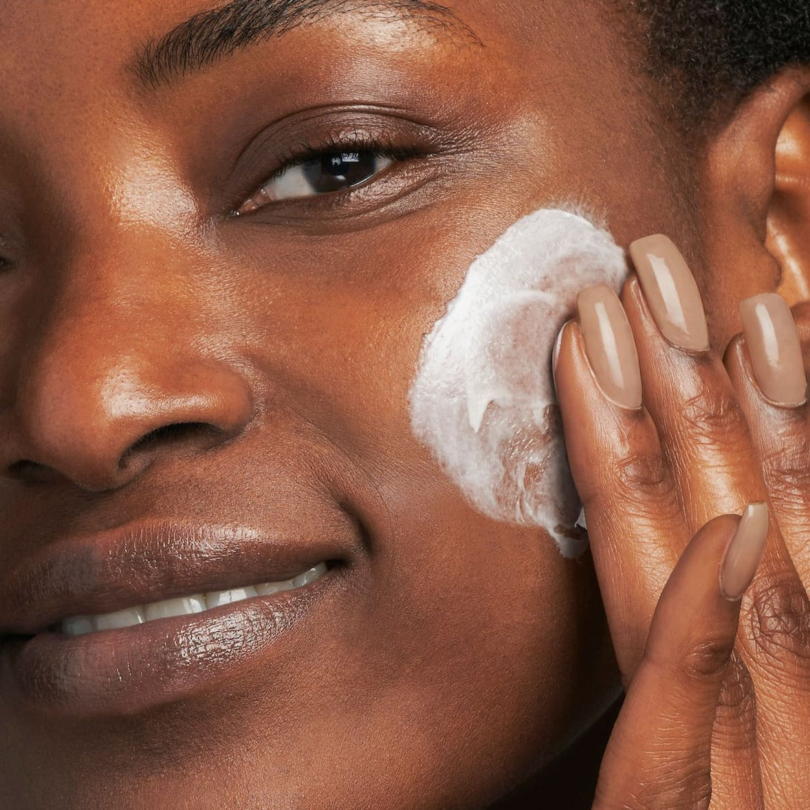 model applying the cream to her cheek