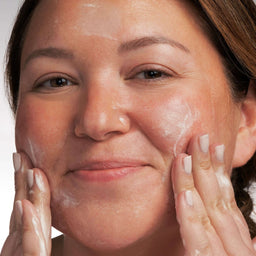 model applying the cleanser to her face