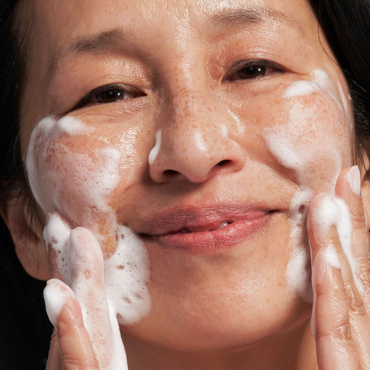 model applying the wash to her face