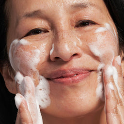 model applying the wash to her face