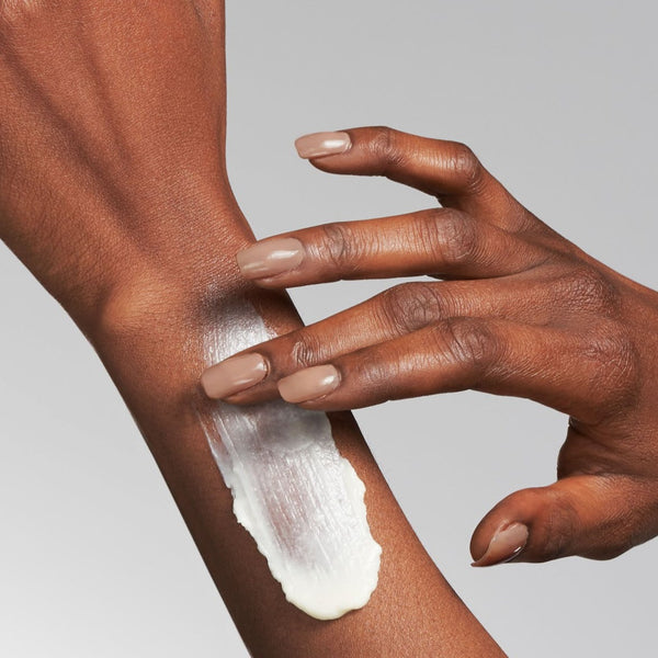 model applying the cream to their arm