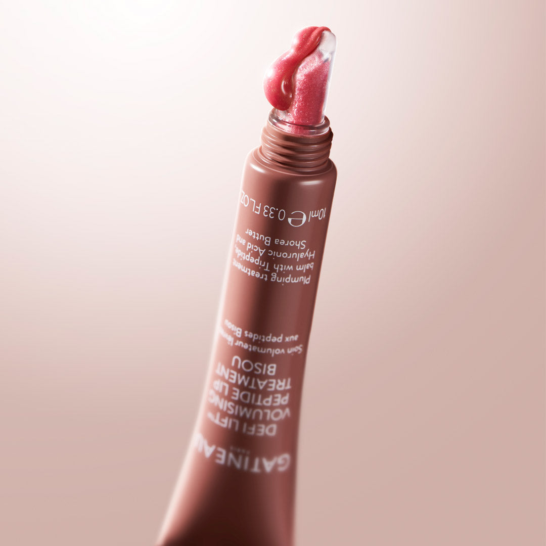 Lip gloss with a pink lip swatch on a beige background