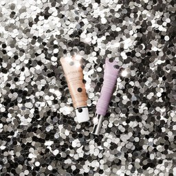 Two lip glosses on a glittery background