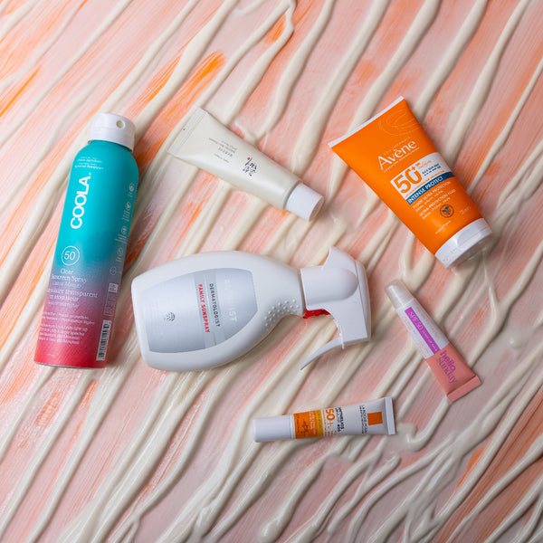 Collection of sunscreen products on a textured peach-colored background