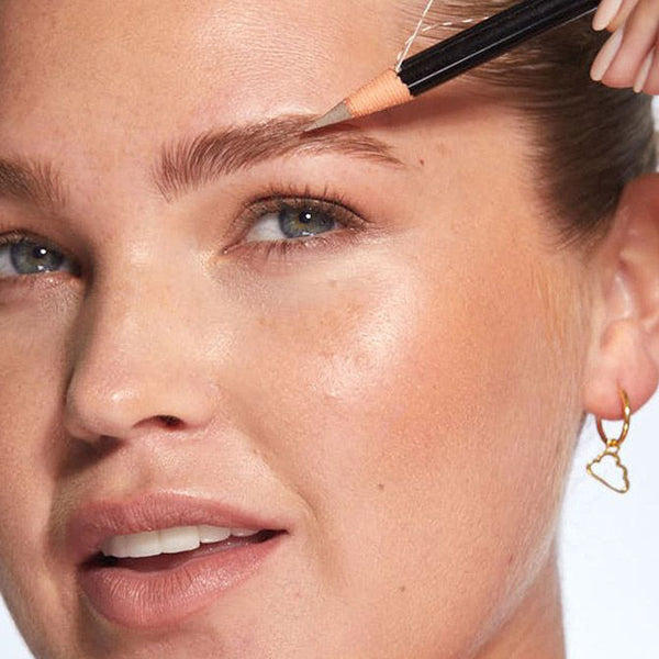 a closeup of a women applying the pencil