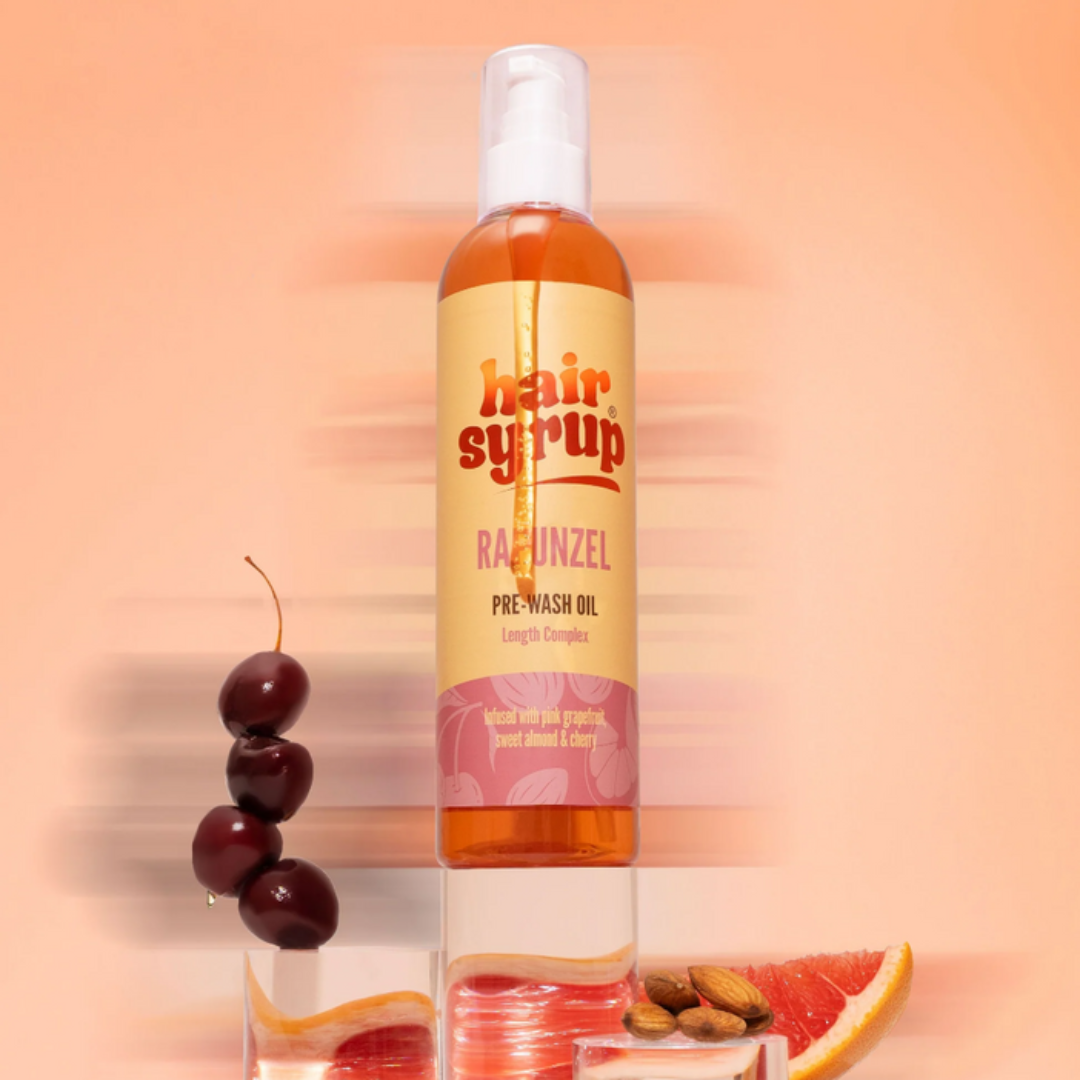 Bottle of 'hair syrup' with a cherry and grapefruit on a peach background
