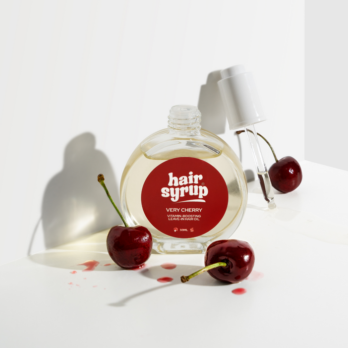 Hair syrup bottle with cherries on a white background