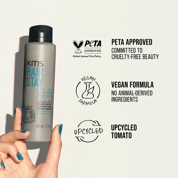KMS Hair Stay bottle held by a hand with PETA approval and vegan formula labels on a light background