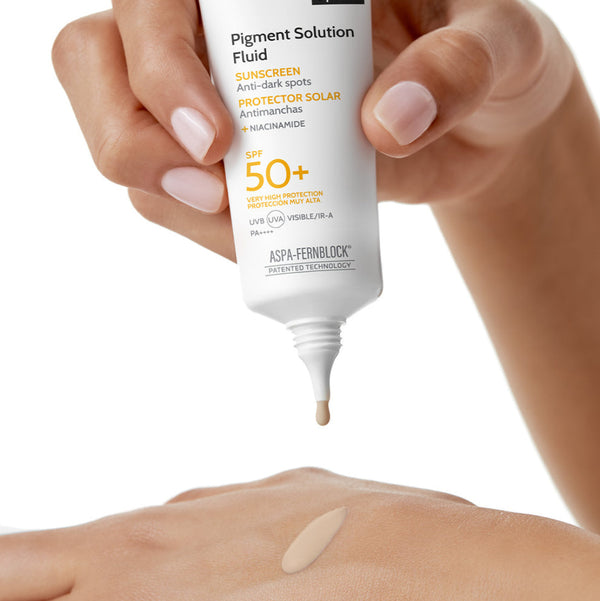 Hand holding a tube of Heliocare 360 Pigment Solution Fluid on a white background