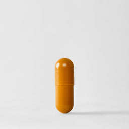 A single orange-yellow capsule pill standing upright on a light gray background.