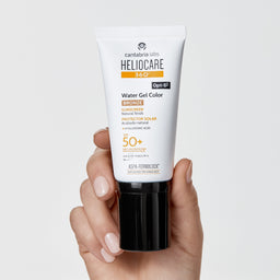 Heliocare sunscreen tube held in a hand with a light gray background
