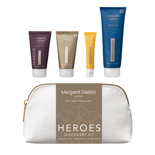 Margaret Dalb's Heroes Discovery Kit featuring four travel-sized toiletry tubes in purple, gold, yellow, and blue, arranged above a white zippered pouch with a brown label.