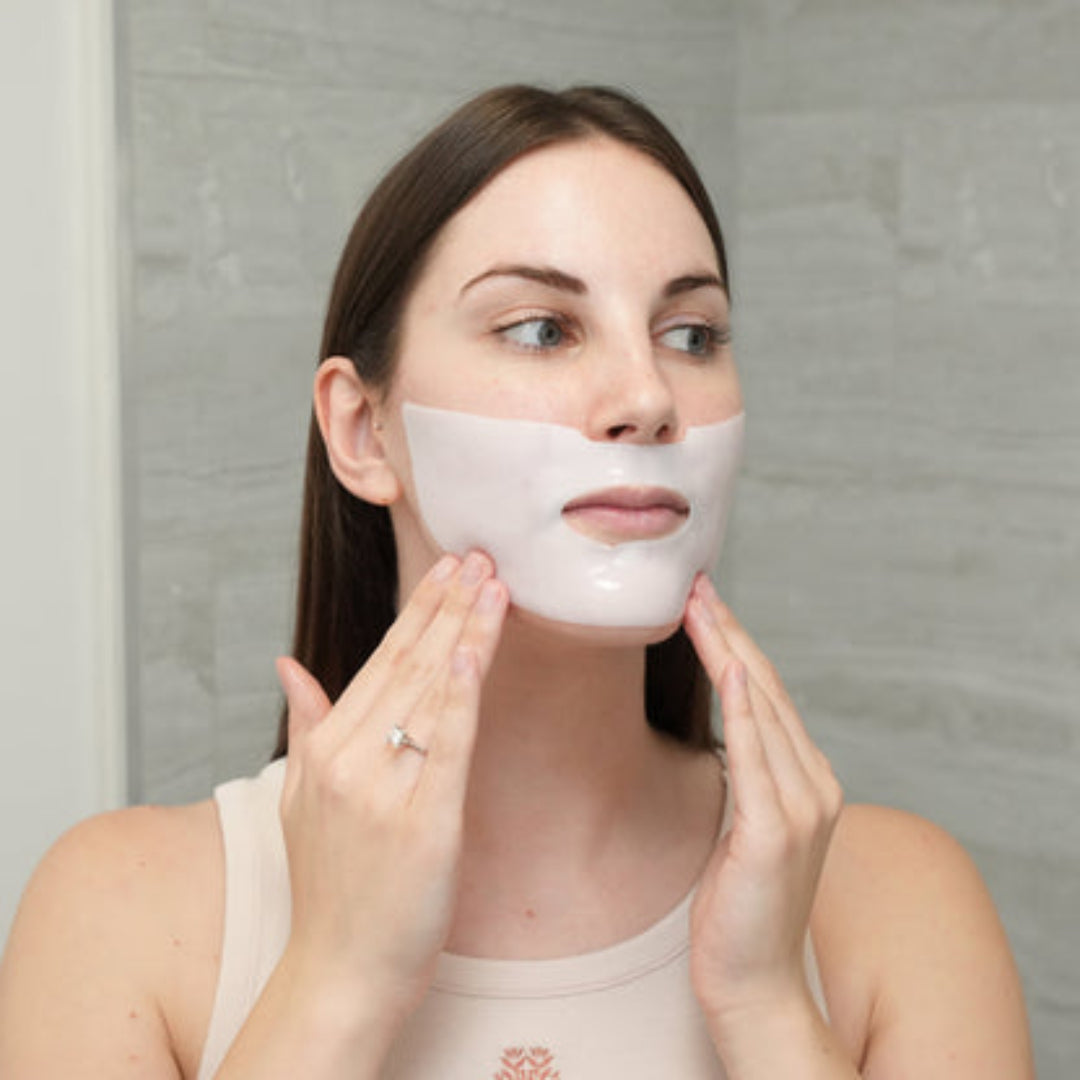 Woman applying a face mask in front of a mirror