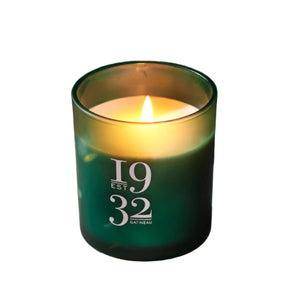 Green candle with '1932 Gatineau' branding on a reflective surface with confetti.