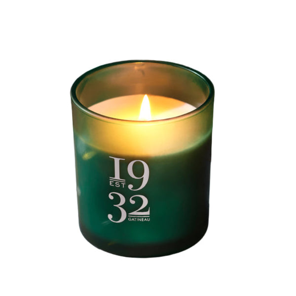 Green candle with '1932 Gatineau' branding on a reflective surface with confetti.