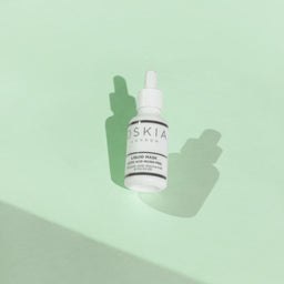 OSKIA Liquid Mask bottle on a green surface