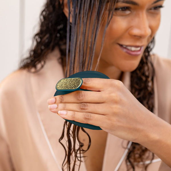 Woman with wet hair using a green hairbrush indoors