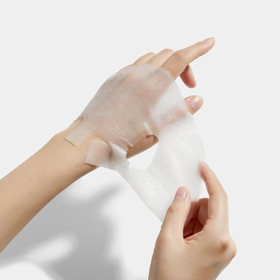 Person applying a white cream or lotion to their hand against a light background