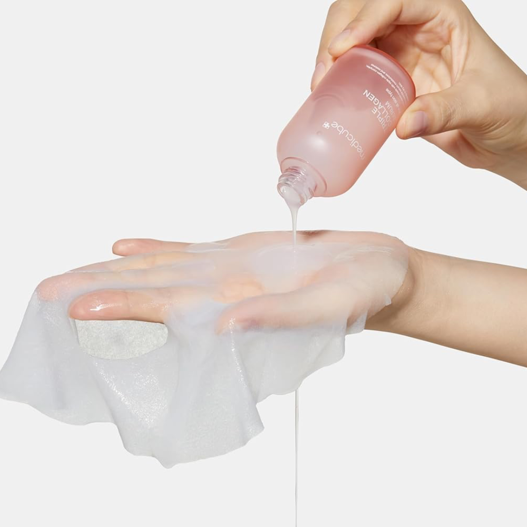 Hand applying a pink bottle of skincare product to a white cloth on a light gray background