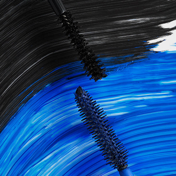 Close-up of mascara brushes with black and blue bristles on a textured background