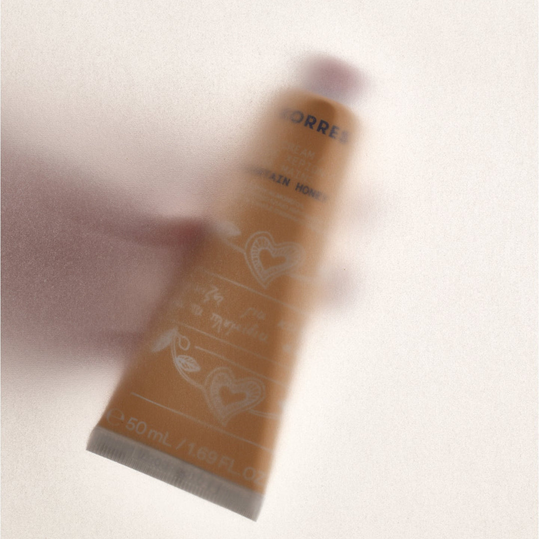 Hand holding a tube of Corres hair product on a light background