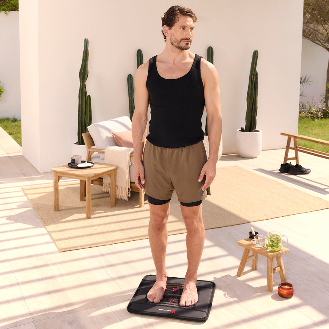 Man using a fitness device on a patio with plants and furniture in the background