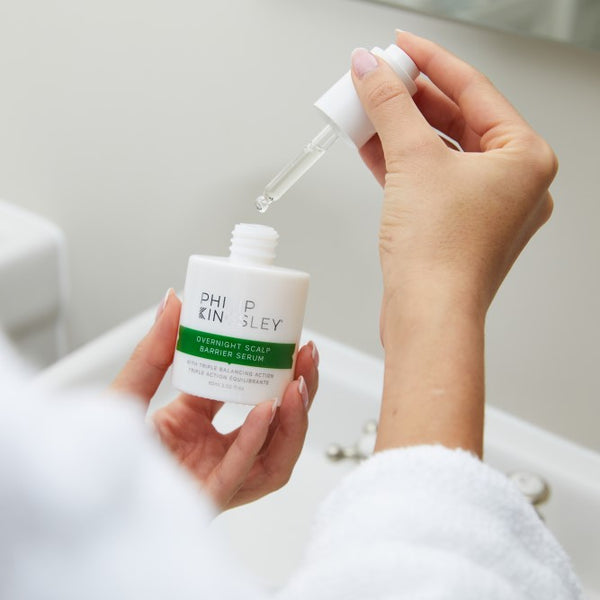 Hand holding a Philip Kingsley skincare product with a dropper.