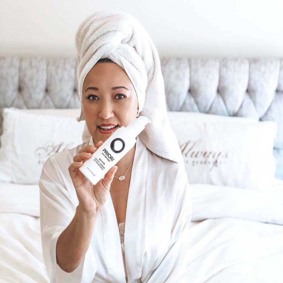 a woman holding a bottle of PRIORI LCA - Gentle Cleanser