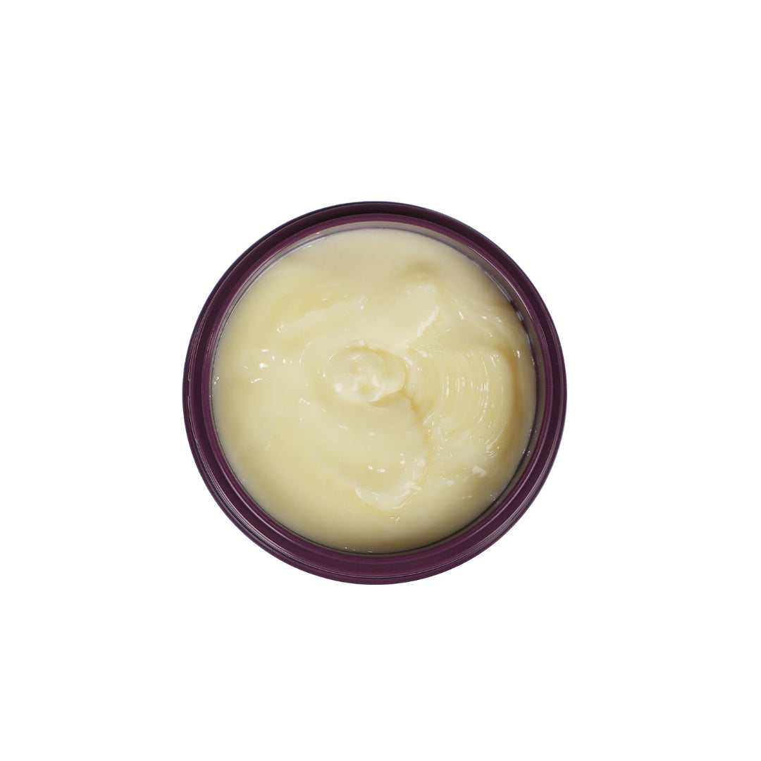 A top-down view of a round jar filled with a pale yellow cream or balm, set against a plain white background.