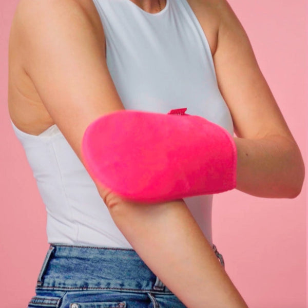 a woman applying tan using the mitt to her arm