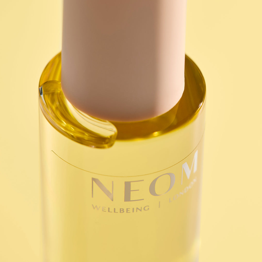 NEOM wellbeing product with a yellow cap on a light yellow background