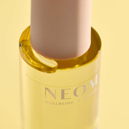NEOM wellbeing product with a yellow cap on a light yellow background