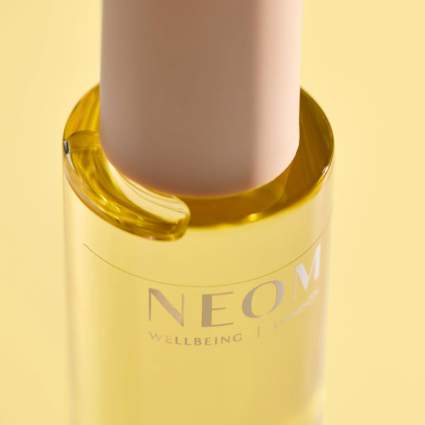 NEOM wellbeing product with a yellow cap on a light yellow background