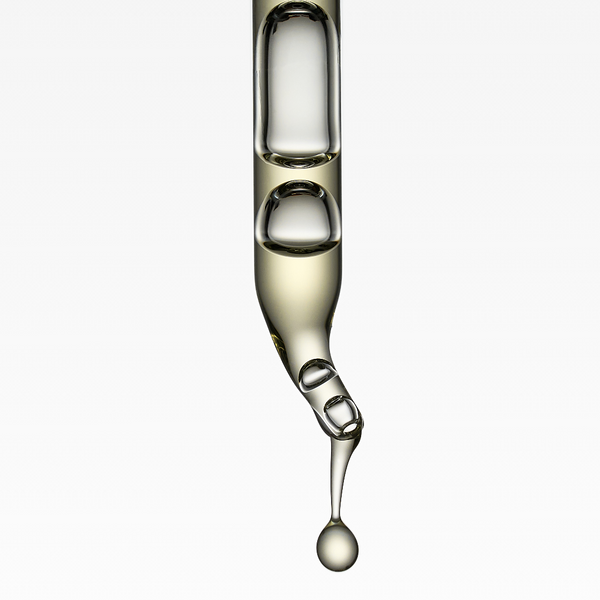 A clear glass dropper pipette containing a pale golden liquid, shown against a plain white background with a single drop hanging from the tip.
