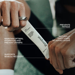Runner holding a sachet of Puresport electrolyte powder with electrolytes benefits with overlay text.